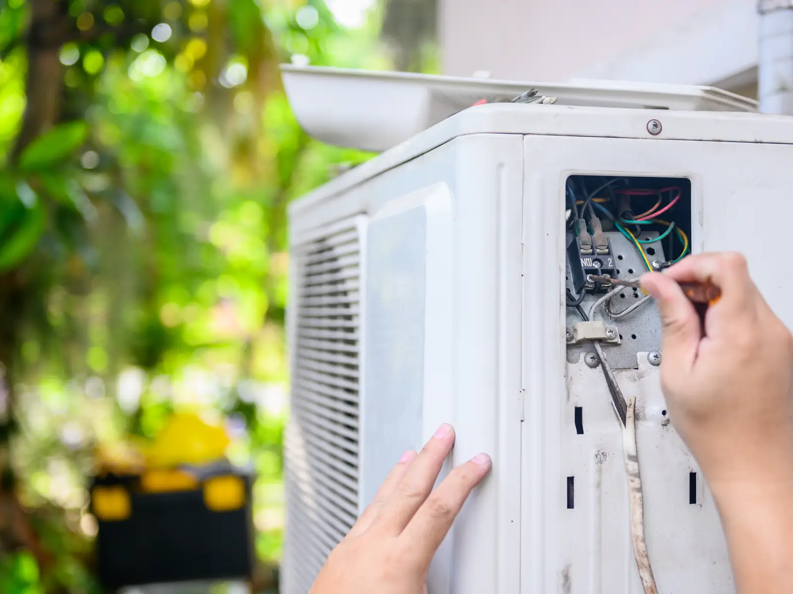 Technicien contrôlant le bornier électrique d'un groupe extérieur de climatisation qui se coupe