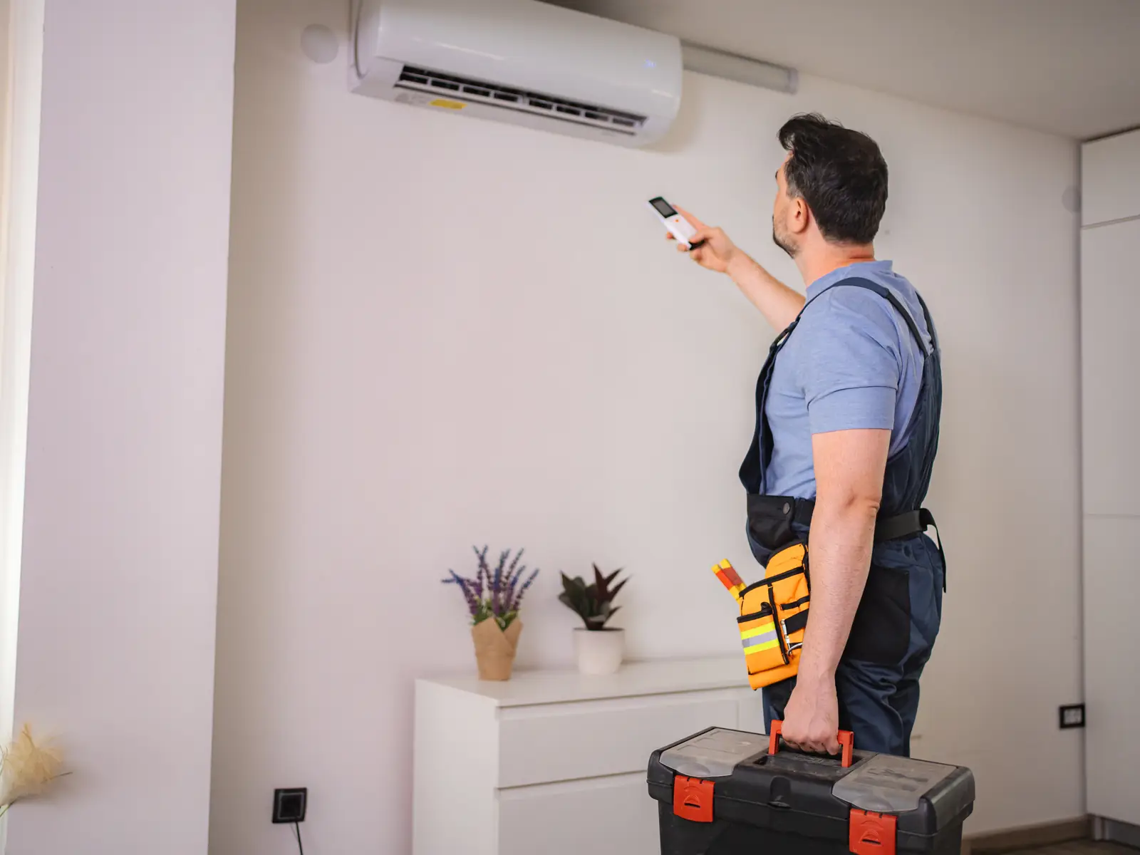 Technicien testant la télécommande d'un climatiseur mural après une réparation