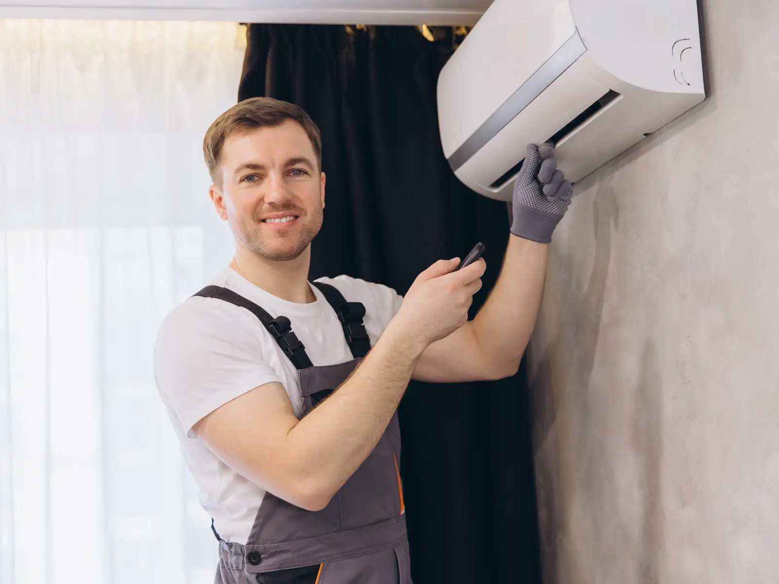 Technicien en train de réparer une unité intérieure de climatisation fixée au mur