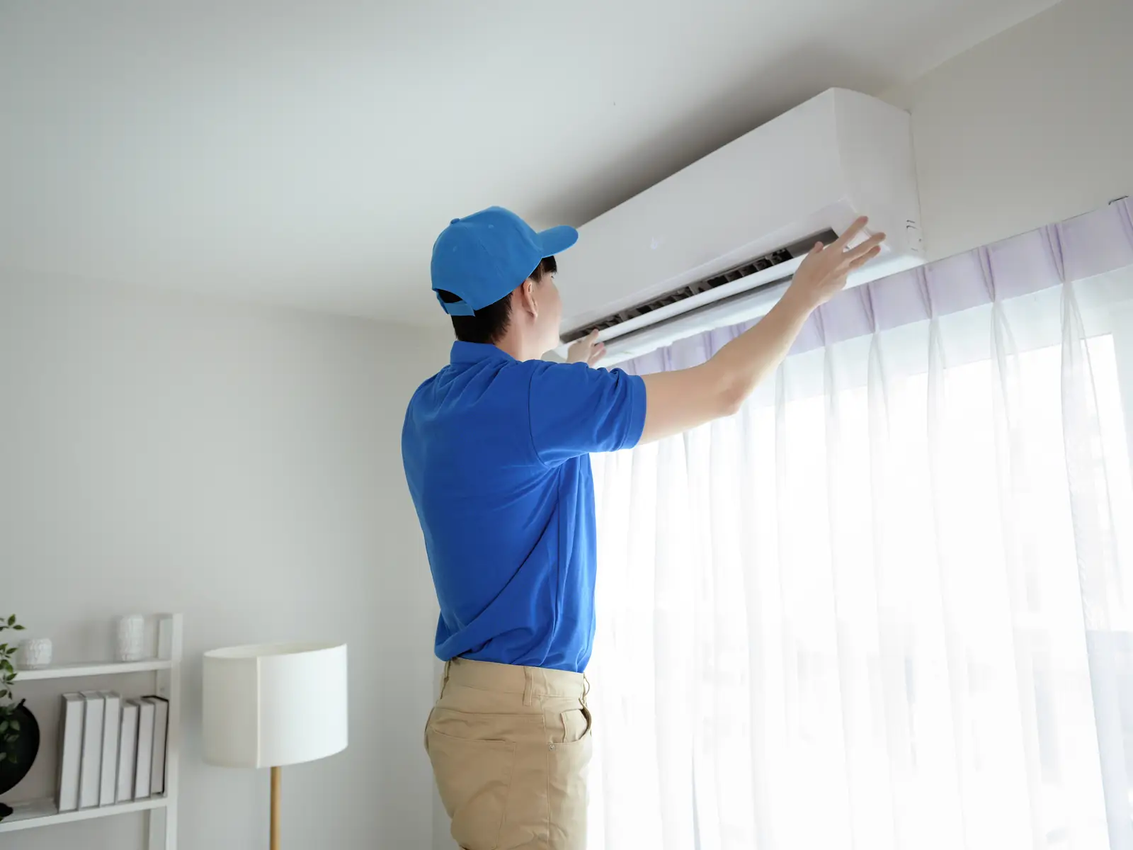 Technicien vérifiant une unité murale de climatisation dans un appartement