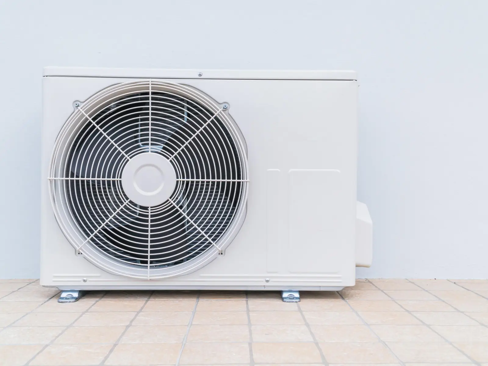 Unité extérieure de climatisation posée au sol contre une maison